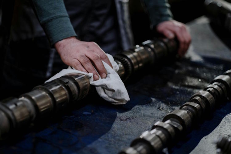 man wiping down mechanical parts in the shop